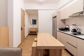 Eine kleine Küche mit Holztisch, Spüle, Kühlschrank und Herd.