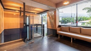Un intérieur moderne avec un ascenseur en verre, un banc et une vue sur l’extérieur.