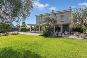 A two-story building with a covered outdoor seating area and a well-maintained lawn. - Boutique Apartment, Toscolano Maderno, Italy (Toscolano Maderno)