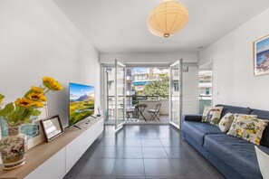 Ein modernes Wohnzimmer mit einer Couch, einem Fernseher und Blick ins Freie.