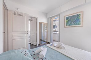 A hotel room with a bed, a painting, and a view of the outside. - Le Plaza Antibes, Antibes, France (Antibes)