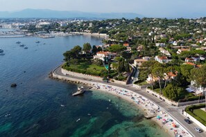 Luftaufnahme einer Küstenstadt mit Strand, Booten und Wohnhäusern.