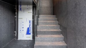 Eine moderne Treppe mit einem gläsernen Aufzug auf der linken Seite und einer Holzdielendecke.