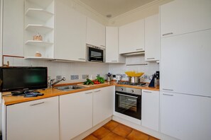 A modern kitchen with white cabinets, a built-in oven, a microwave, and a sink. - Respiro Di Mare Cavi Di Lavagna, Lavagna, Italy (Lavagna)