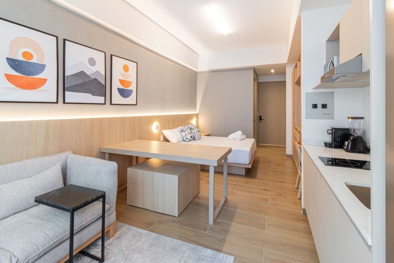 Ein modernes Hotelzimmer mit einer Couch, einem Bett, einem Schreibtisch und einer Küchenzeile.