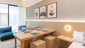 Ein modernes Hotelzimmer mit Essbereich, einer Couch und Kunstwerken an der Wand.