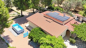 Um imóvel residencial com piscina, painéis solares e telhado de telhas vermelhas.