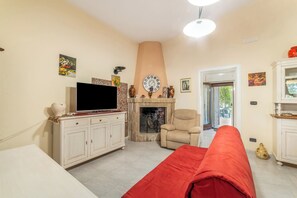 Ein Wohnzimmer mit Fernseher, Sofa, Kamin und einer Tür zum Garten.