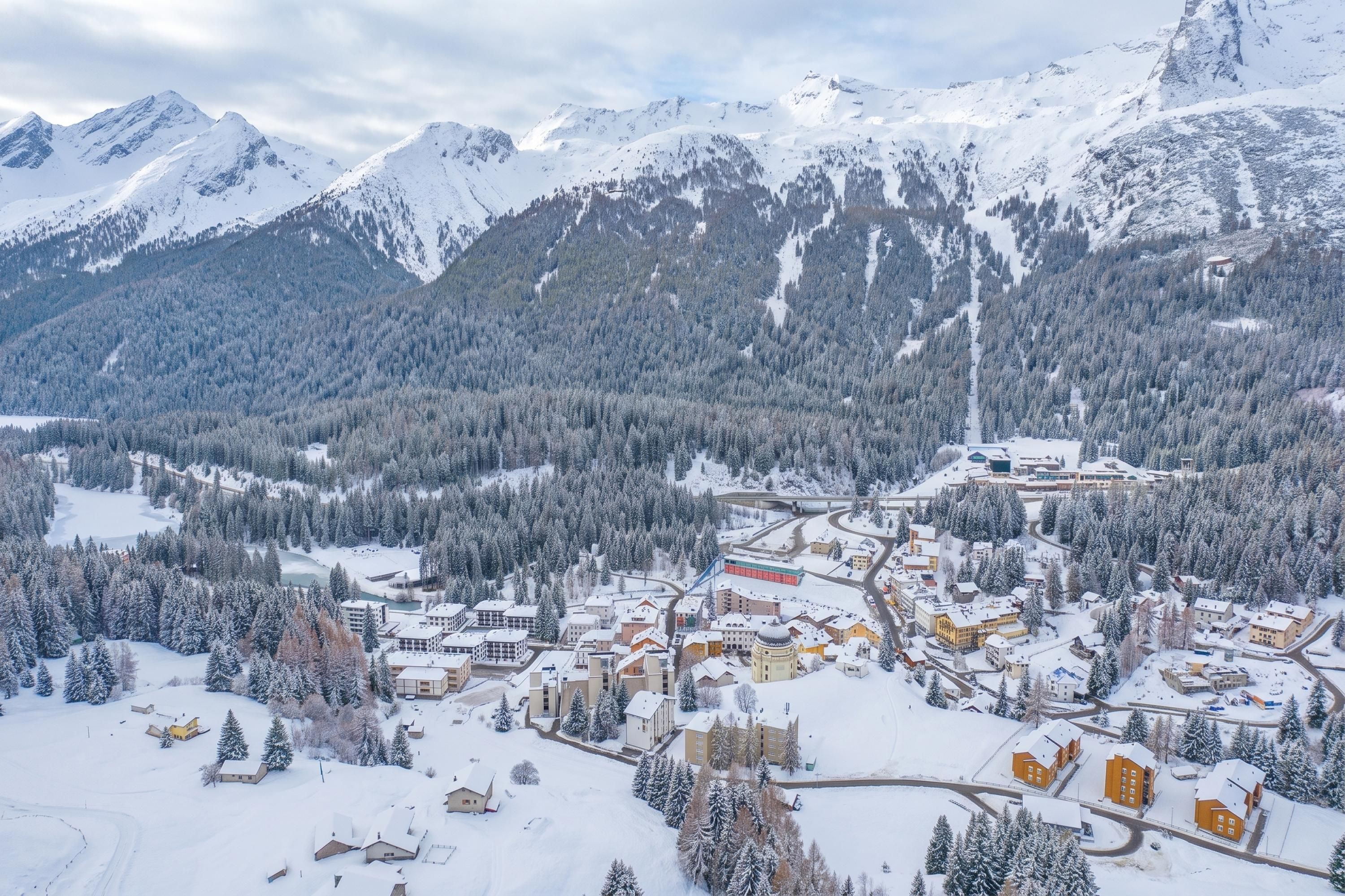 Une ville de montagne enneigée, avec des bâtiments et des routes.