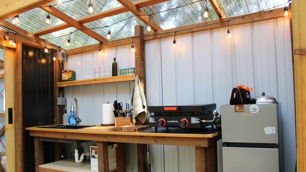 A kitchen with a wooden countertop, a gas stove, a refrigerator, and a skylight above.