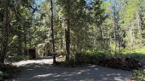 A gravel path leading into a forested area with a welcome sign.