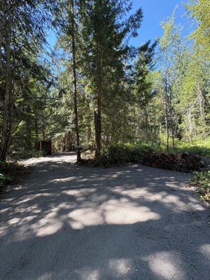 A gravel path leading into a forested area with a welcome sign.