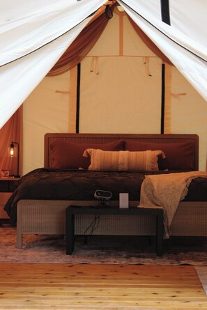 Una habitación con carpa, una cama, una mesita de noche y una lámpara.