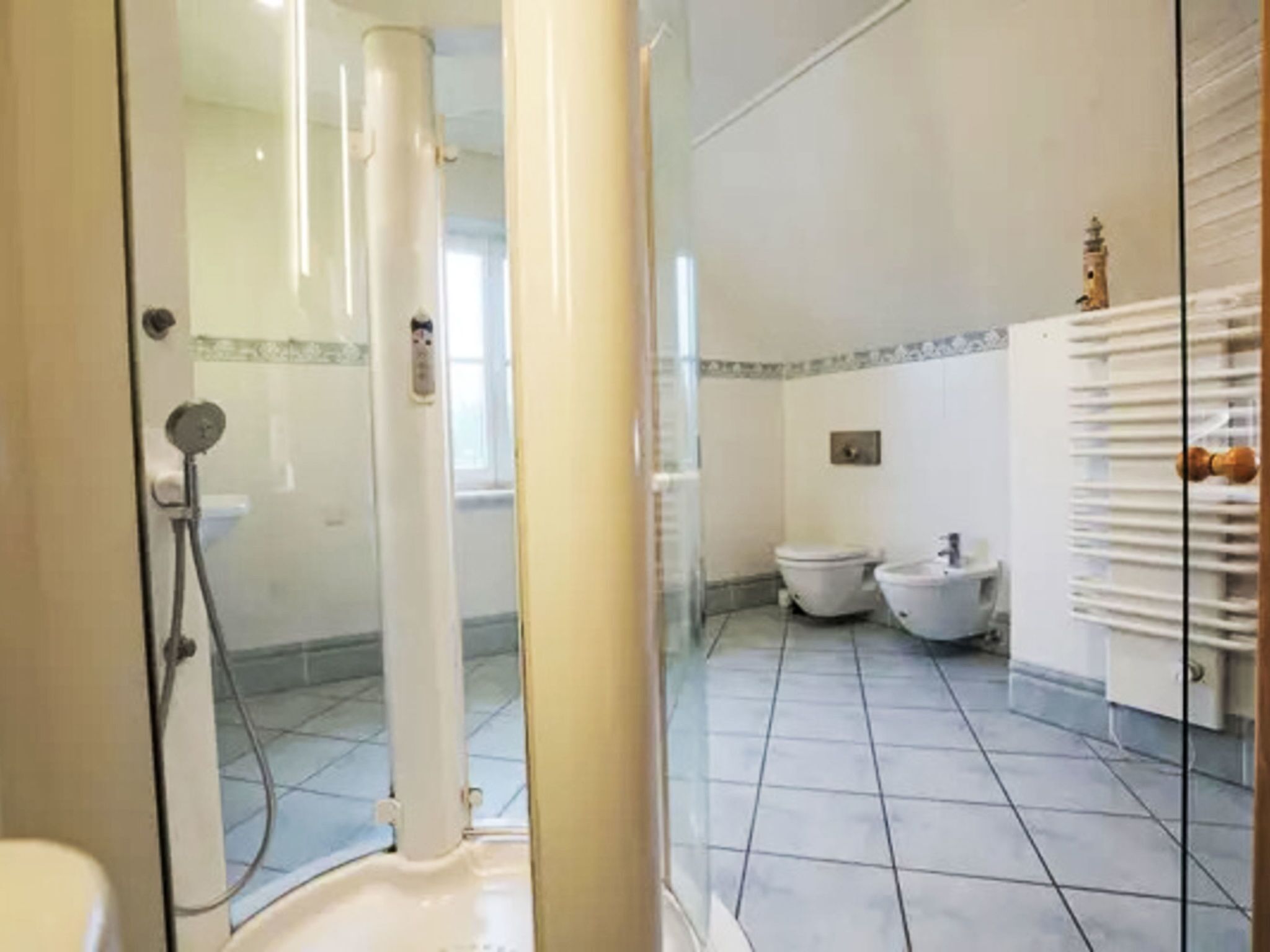 Een badkamer met een douchecabine van glas, een toilet en een douchetoilet.