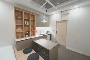 A compact kitchenette with a microwave, sink, and a small dining area with stools.