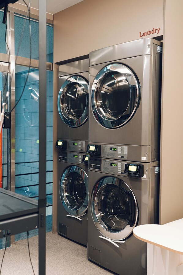 A laundry area with four front-loading washing machines and a wall-mounted dryer.