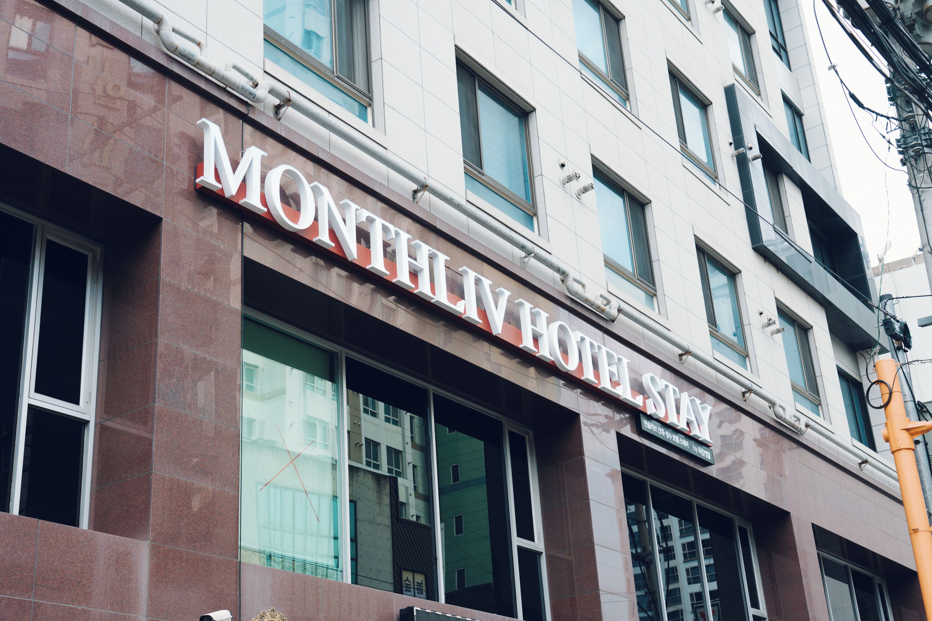 Un edificio con un letrero que dice 'MONTHLY HOTEL STAY'.