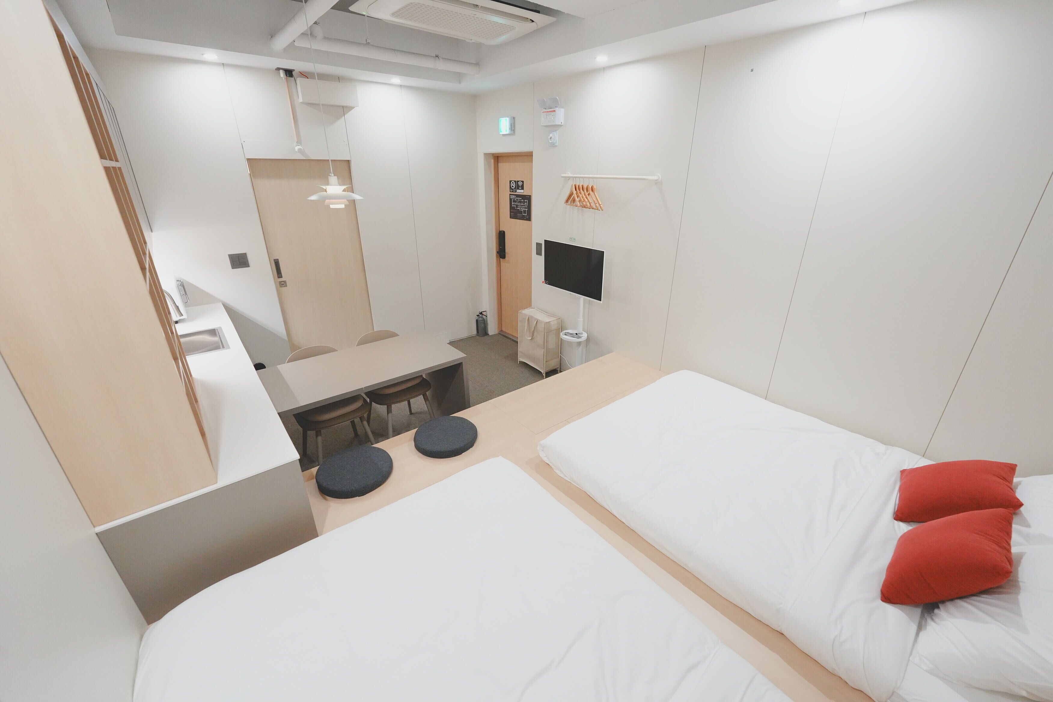 A hotel room with two beds, a desk, and a TV.