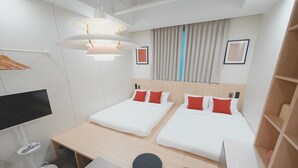 Habitación de hotel con dos camas, un escritorio, un televisor y un pequeño rincón de descanso.