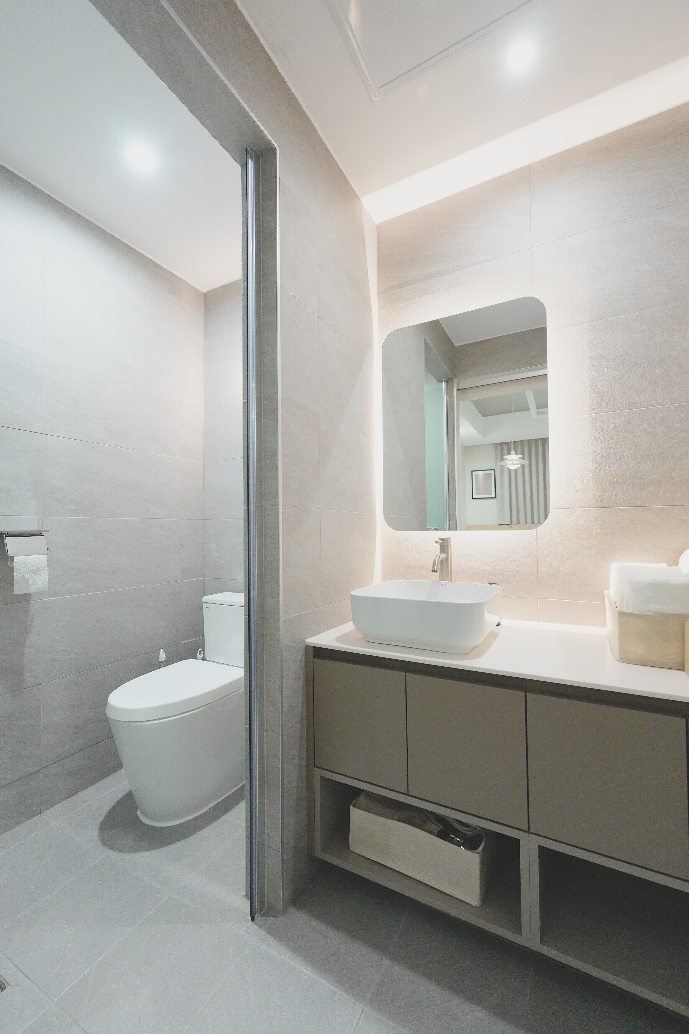 A modern bathroom with a toilet, a sink, and a mirror.