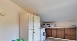 Ein Waschraum mit Waschmaschine, Schränken und einer Arbeitsplatte mit verschiedenen Gegenständen.