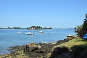 Eine Küstenlandschaft mit ruhigem Wasser, Booten und einer felsigen Küste.