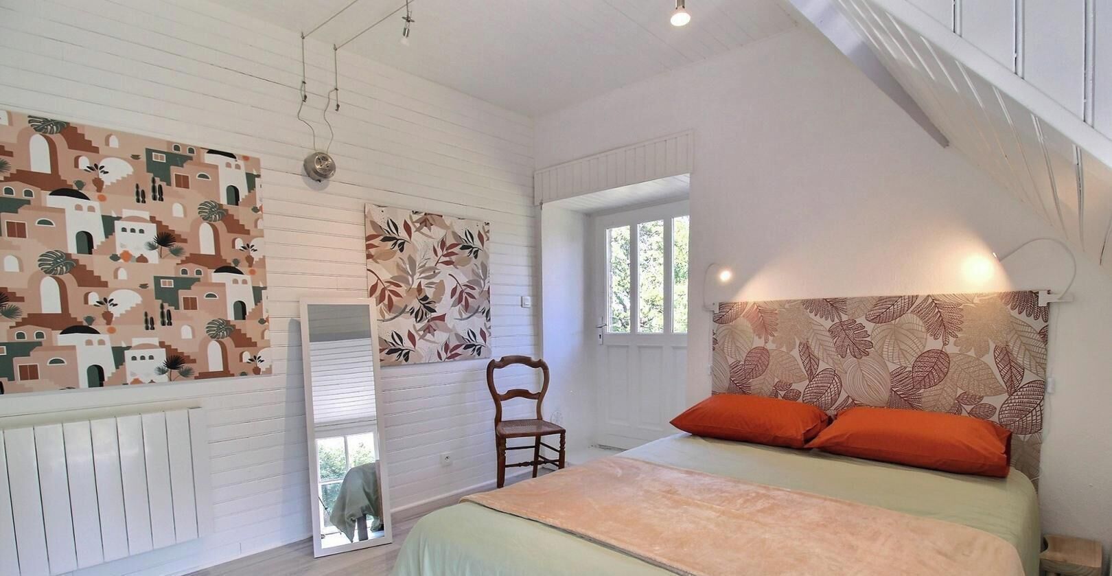 A bedroom with a bed, a chair, a window, and a door.