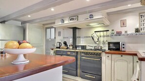 A kitchen with a central island, a stove, oven, microwave, and various kitchen utensils. - Ty Venoux - ELVEN - Vacation Rental (ELVEN)