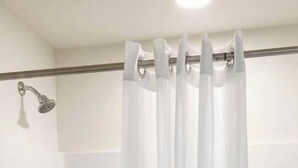 Un baño con cortina de ducha, bañera y toallero.