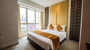 Habitación de hotel con una cama grande, vista de la ciudad a través de una ventana y un papel tapiz estampado.
