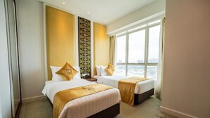 Habitación de hotel con dos camas, un ventanal grande y vista a la ciudad.