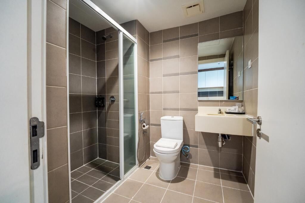 A bathroom with a shower, toilet, sink, and a mirror.