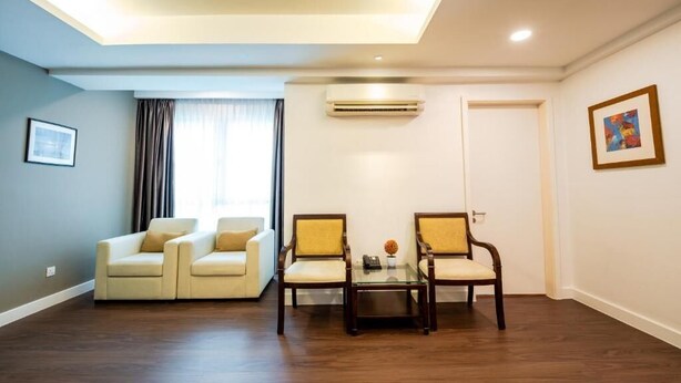 A room with a sofa set, two chairs, a small table with a vase, and an air conditioning unit. - Utm Hotel Residence (Kuala Lumpur)