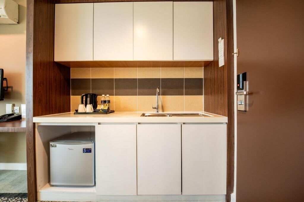 Una kitchenette compacta con un refrigerador integrado, una cafetera y un lavamanos.