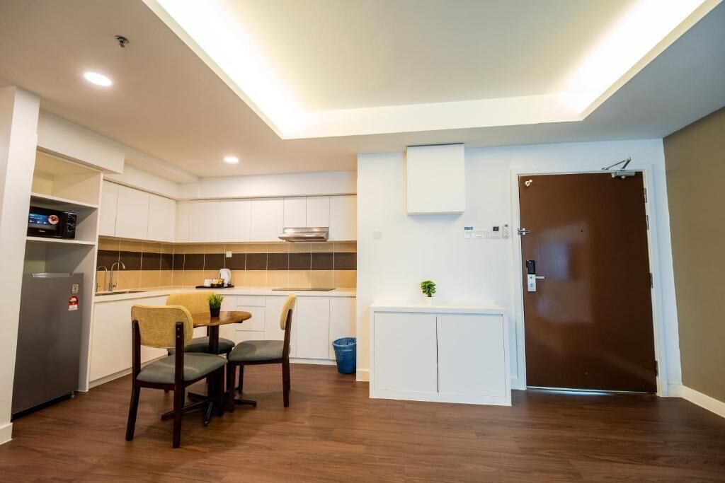 Cocina compacta con comedor, horno empotrado y refrigerador pequeño.