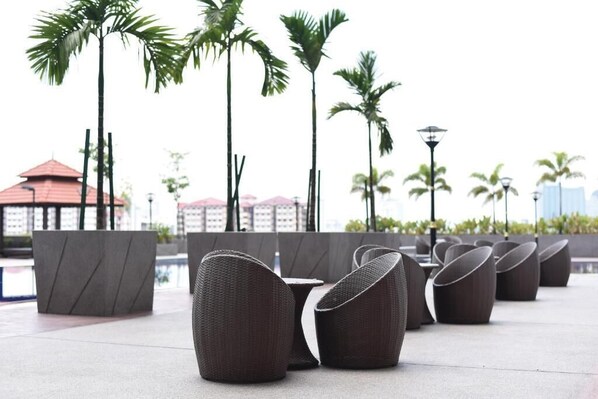 Terraza al aire libre con vista a palmeras y edificios al fondo.