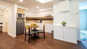 Una cocina moderna con comedor, suelo de madera y muebles de cocina blancos.