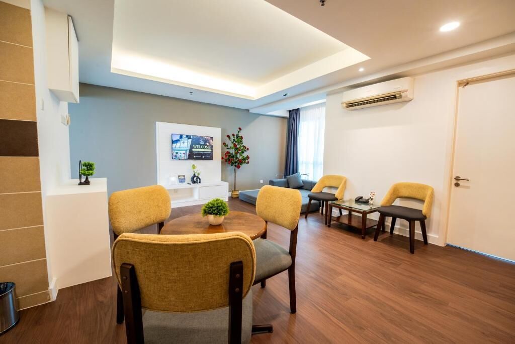 A modern hotel room with a dining area, a sofa set, and a small table with chairs.