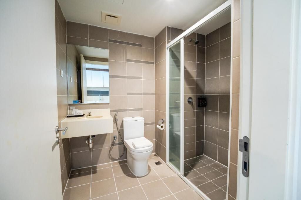 Un baño moderno con inodoro, lavamanos y ducha con mampara de vidrio.