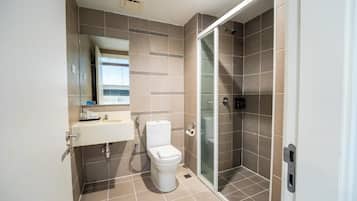 Un baño moderno con inodoro, lavamanos y ducha con mampara de vidrio.