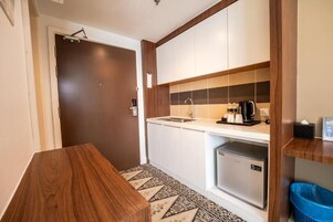 A compact kitchen with a built-in refrigerator, a sink, and a coffee maker on the countertop.