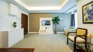 Una sala de estar moderna con un televisor de pantalla plana, un sofá, una mesa de centro y una planta en maceta.