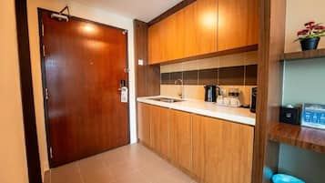 A compact kitchen with wooden cabinets, a sink, and a coffee maker.