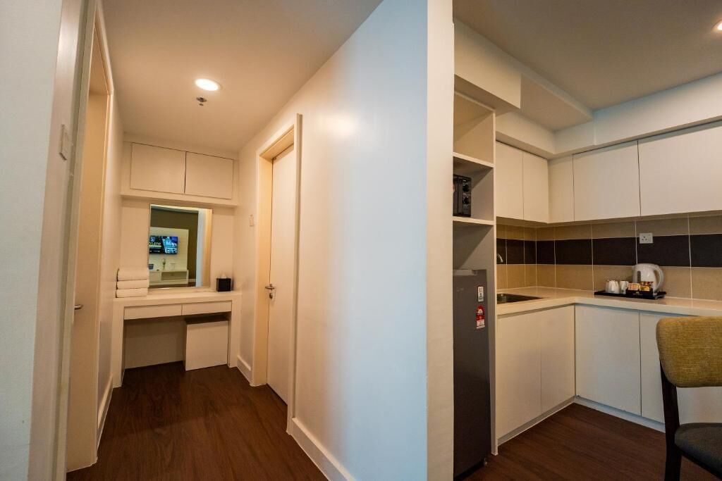 A compact kitchen with white cabinets, a built-in oven, and a coffee maker.