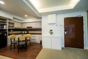 A modern kitchen with built-in cabinets, a dining area with two chairs, a small potted plant, and a brown door.