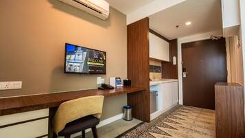 A reception area with a wooden desk, a chair, a television displaying a welcome message, and a patterned carpet.