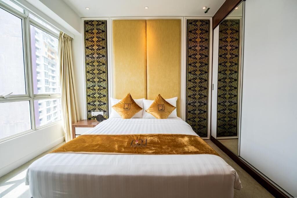 Habitación de hotel con una cama grande, vista de la ciudad a través de una ventana y un cabecero decorativo.
