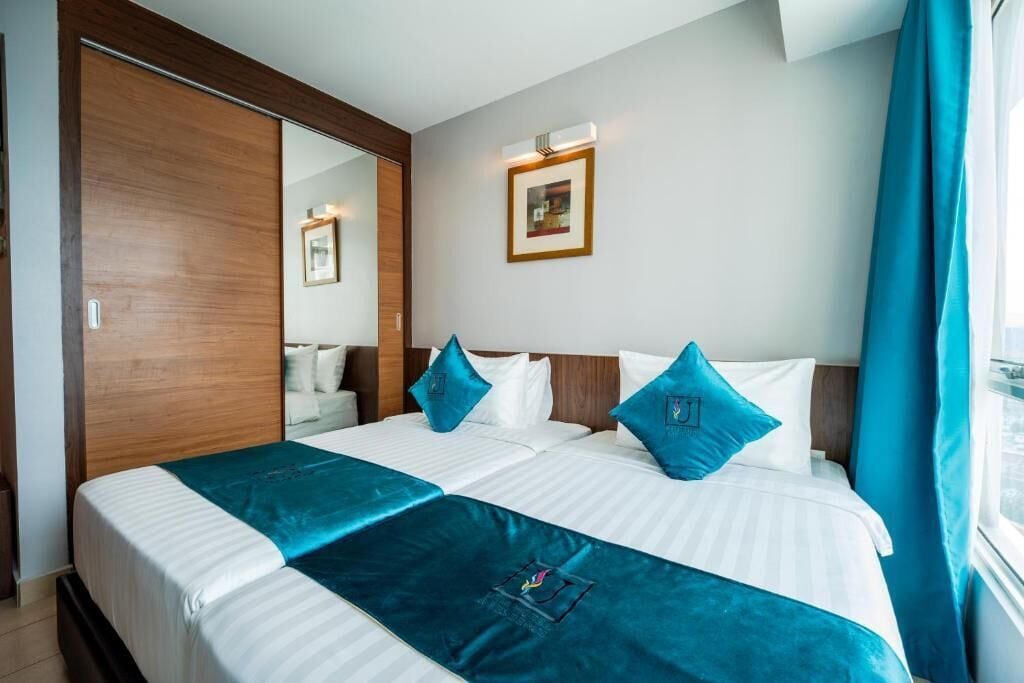 A hotel room with a large bed, a wardrobe, a mirror, and a picture on the wall.