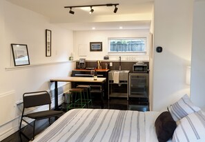 A compact hotel room with a bed, a desk with a chair, a kitchenette, and a small window. - Welcoming 1-bedroom studio in Anchorage perfect for your getaway (Anchorage)
