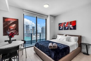 Quarto de hotel moderno com uma cama grande, uma escrivaninha e vista para a cidade.